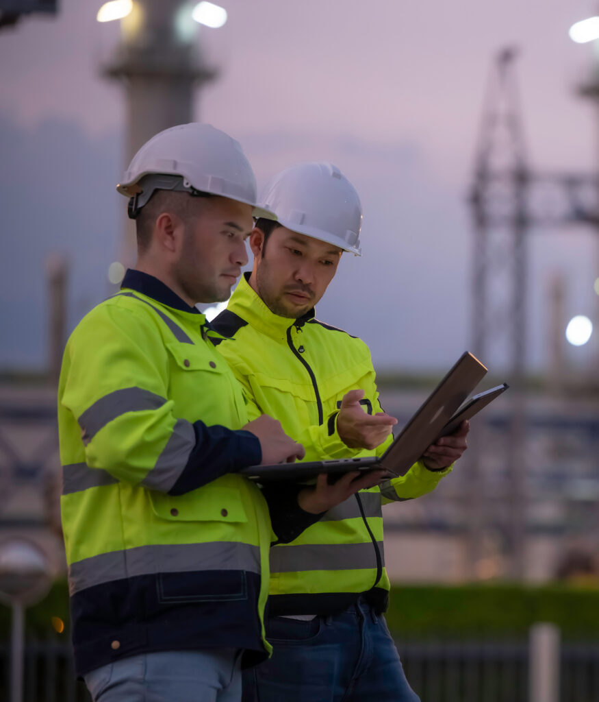engineers using a digital tablet at a petrochemical plant